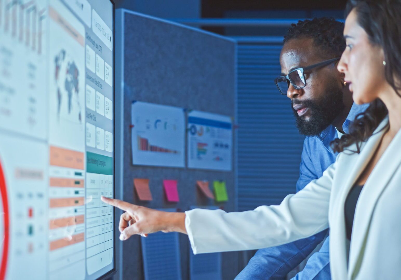 Man analyzing data on a large digital screen with graphs and charts.