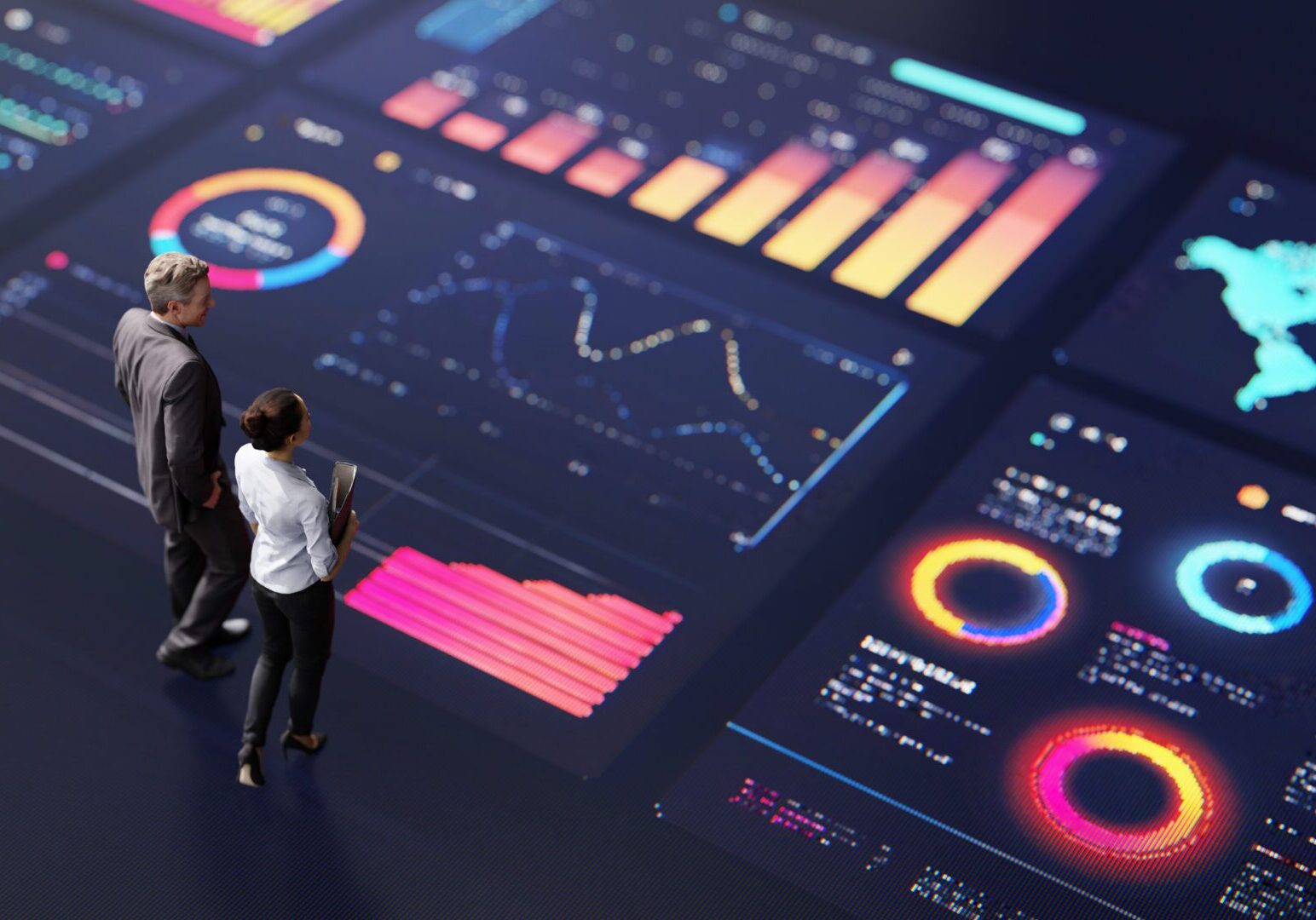 Two people analyze futuristic data visualizations on a large digital screen.